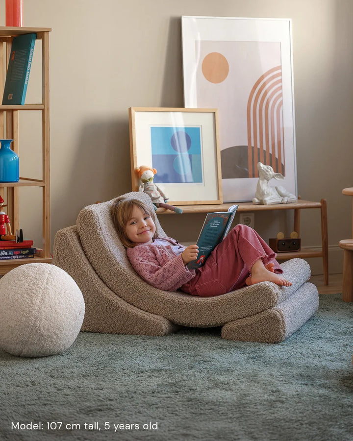 Child relaxing in Wigiwama Biscuit Moon Chair in a cosy home interior