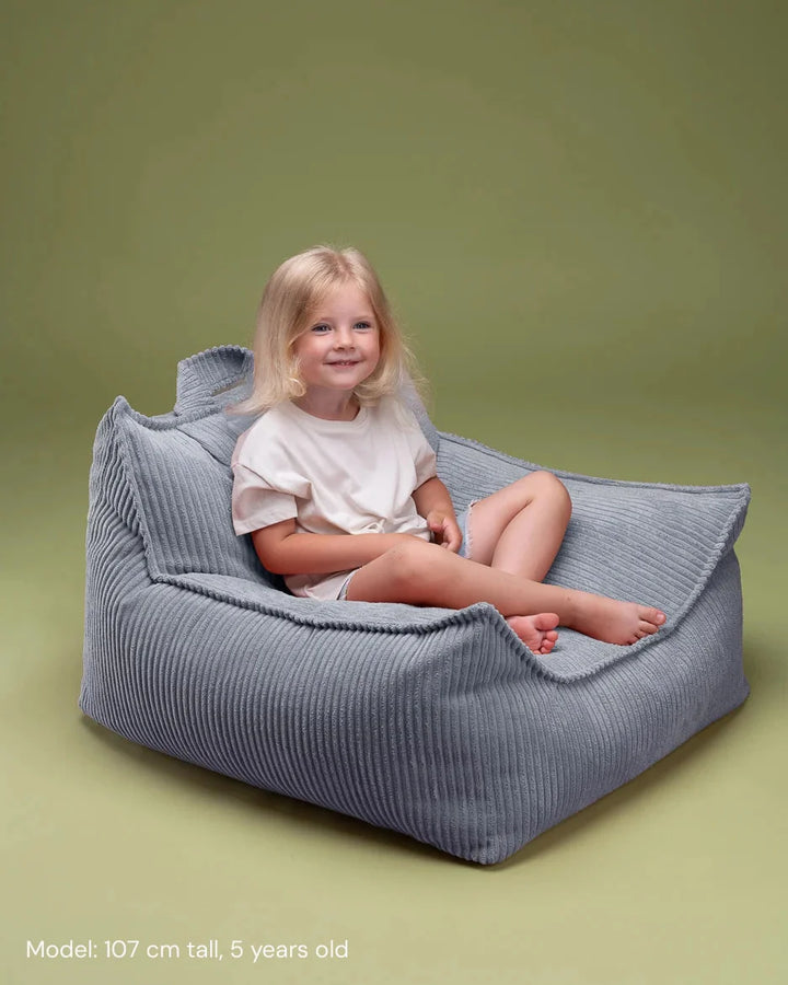 Child relaxing in Wigiwama Blueberry Blue Beanbag Chair in a cosy home interior