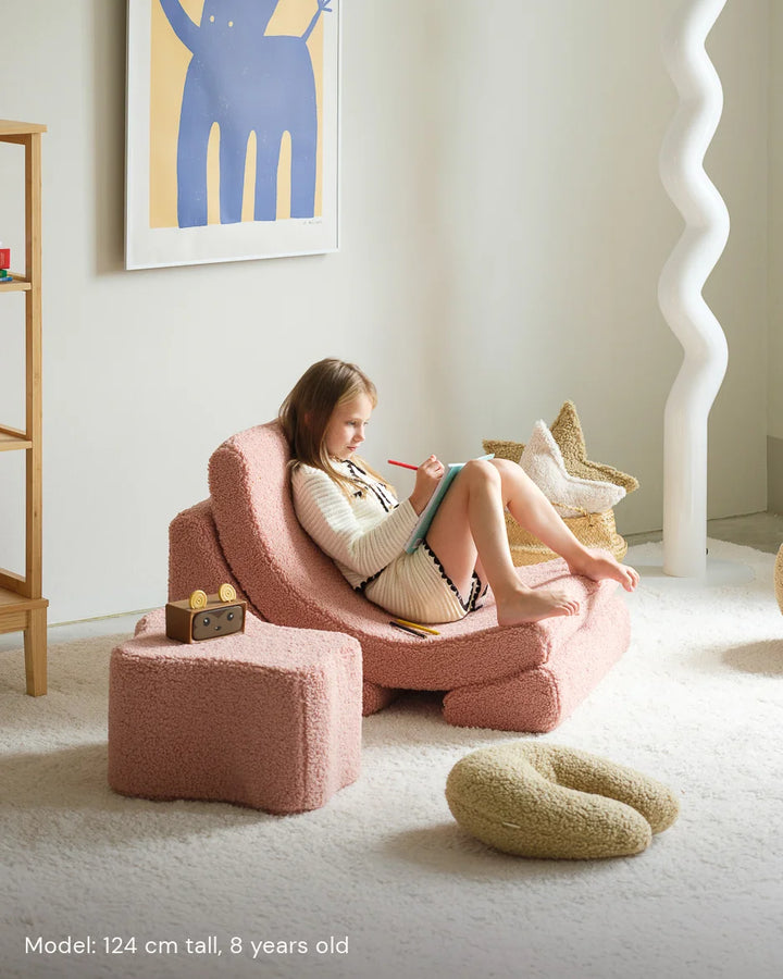 Child relaxing in Wigiwama Guava Moon Chair in a cosy home interior