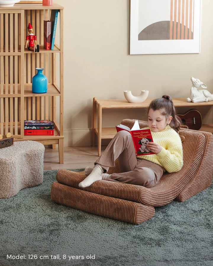 Child relaxing in Wigiwama Toffee Moon Chair in a cosy home interior
