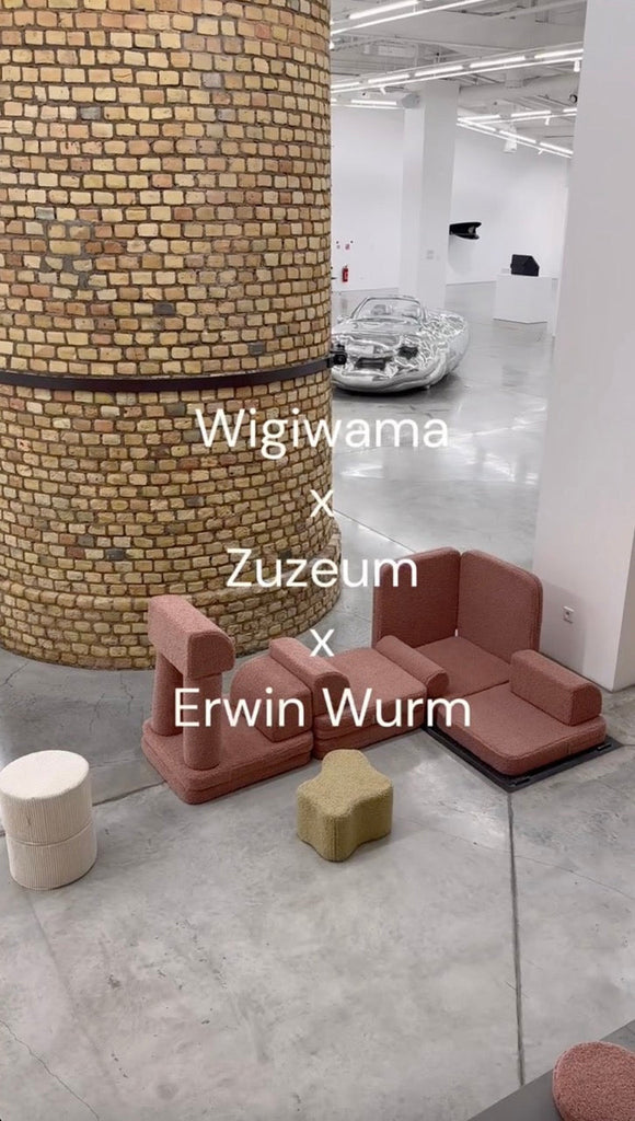 Wigiwama soft furniture arranged around a large brick column inside Zuzeum Art Centre, with a silver Erwin Wurm sculpture in the background and white text overlay naming the collaboration.