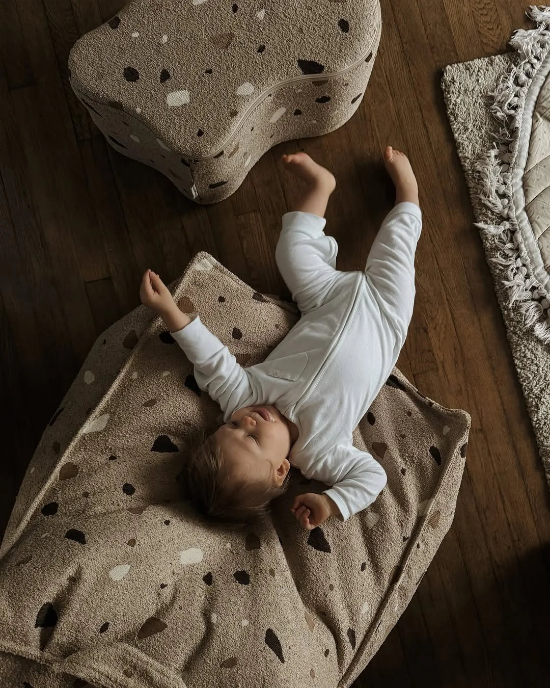 Baby lying on Terrazzo Wigiwama beanbag, surrounded by warm tones