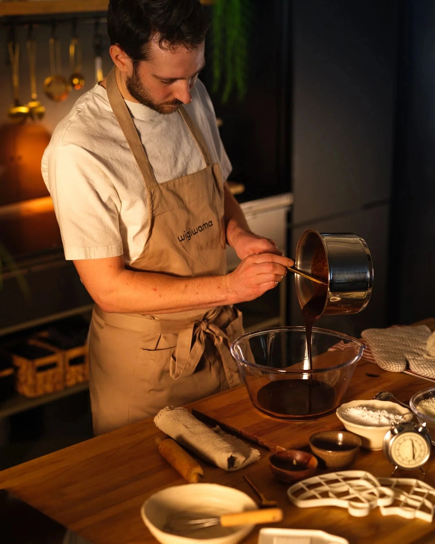 Man in a kitchen pouring liquid from a pot into a bowl.
