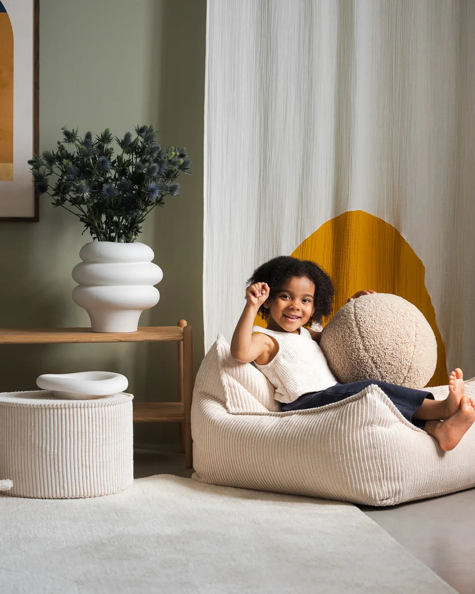 Child sitting on a bean bag chair in a cozy living room setting