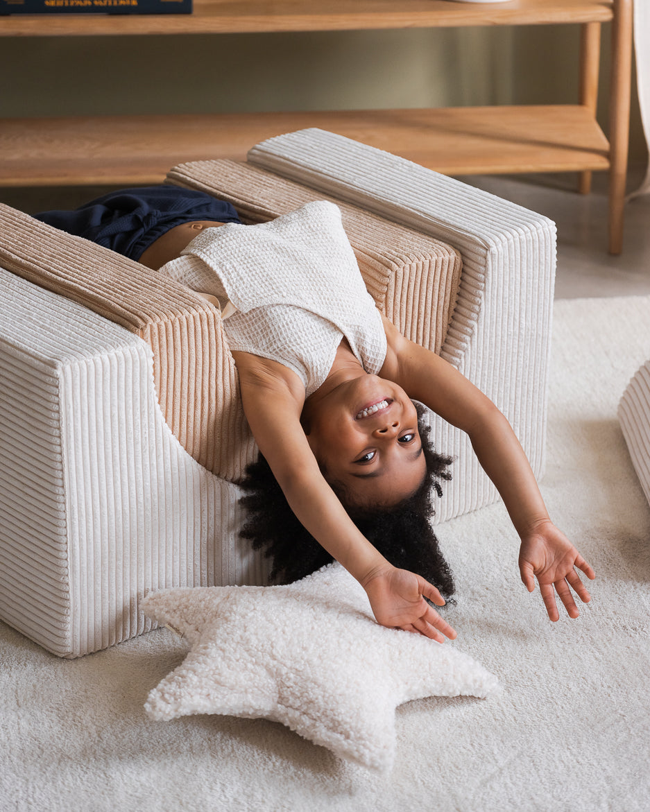 Child is playig on a Playset, next to it is a star cushion. 