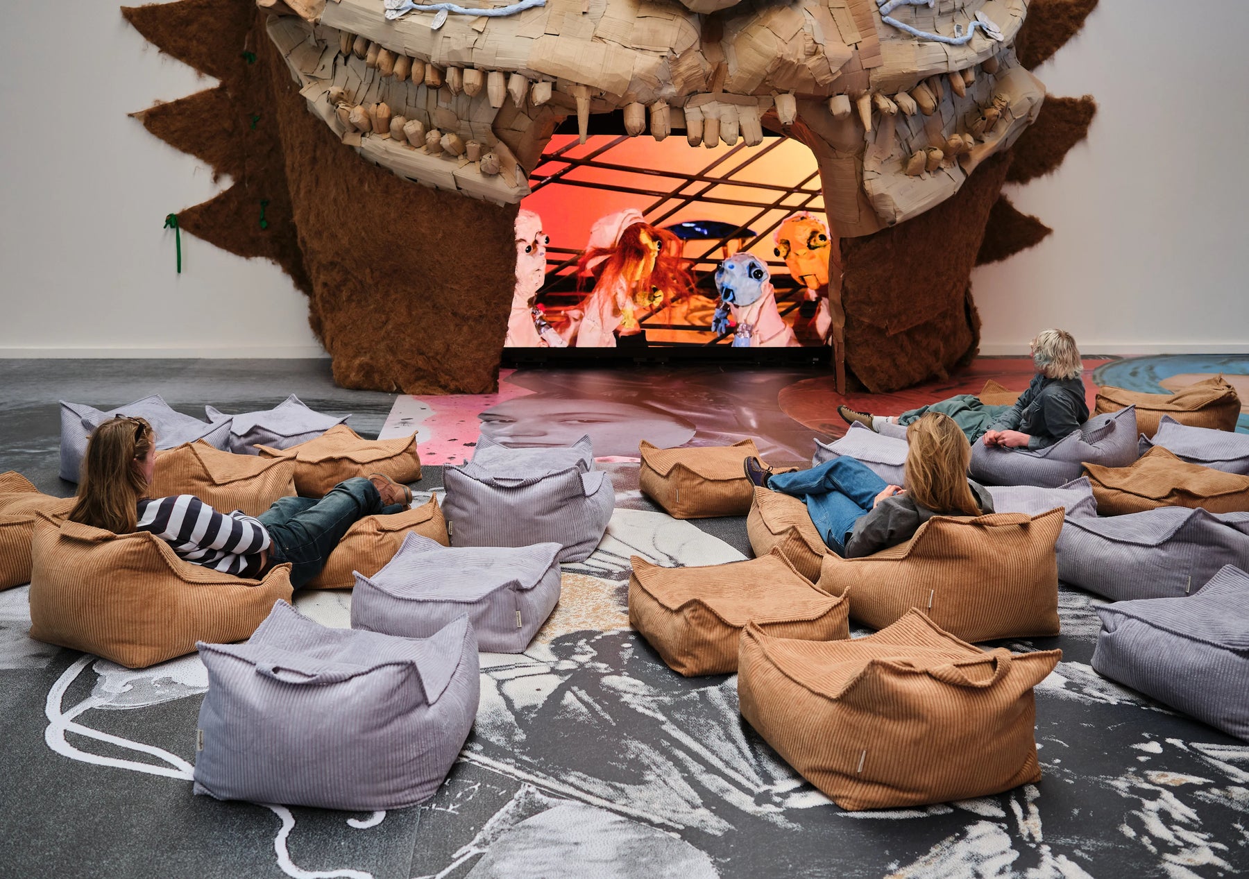 Visitors chilling on Wigiwama beanbags watching a surreal puppet film inside Monster Chetwynd’s installation at Copenhagen Contemporary