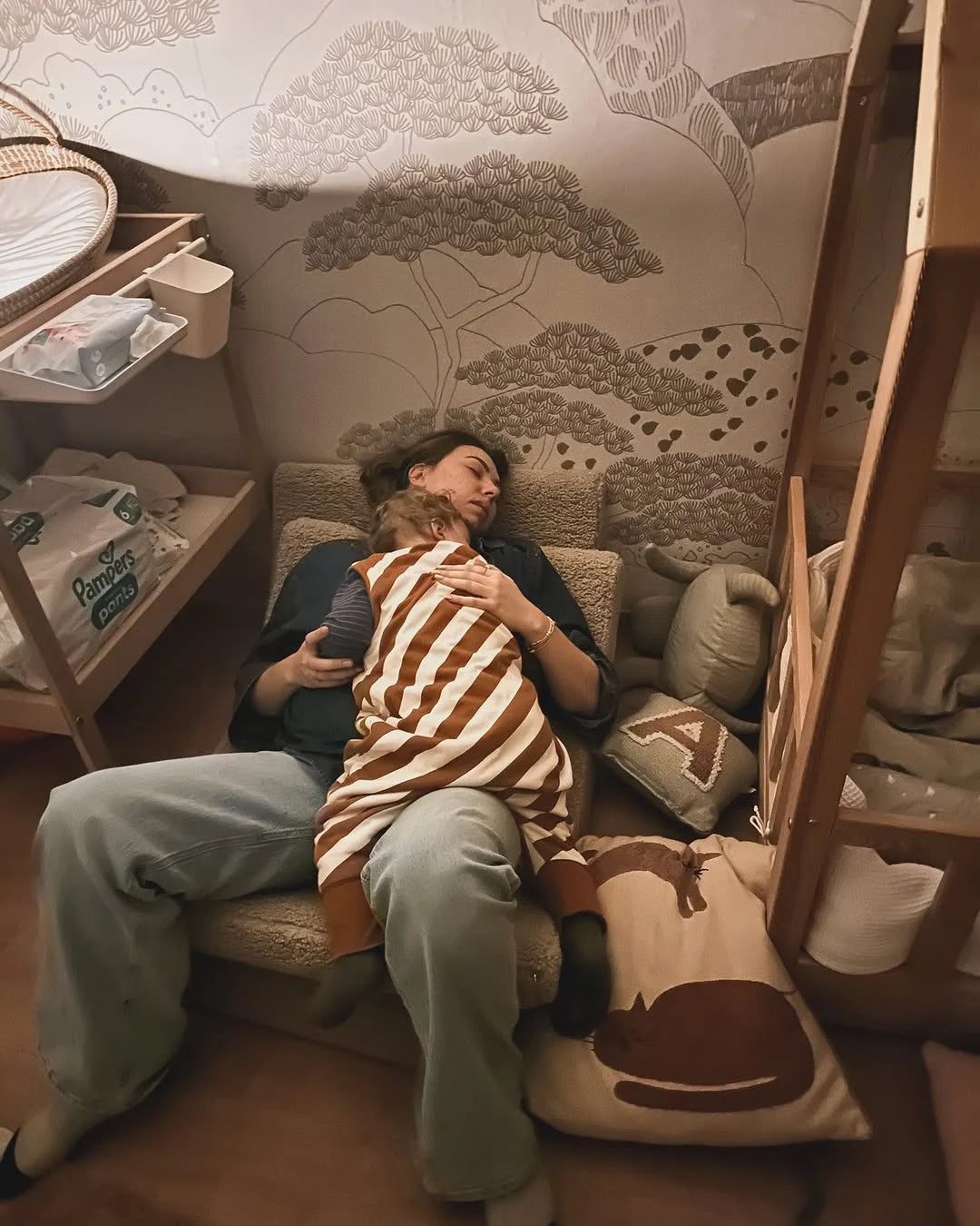 Mother relaxing with her baby on a Wigiwama Moon Chair, surrounded by toys in a cosy corner of the nursery