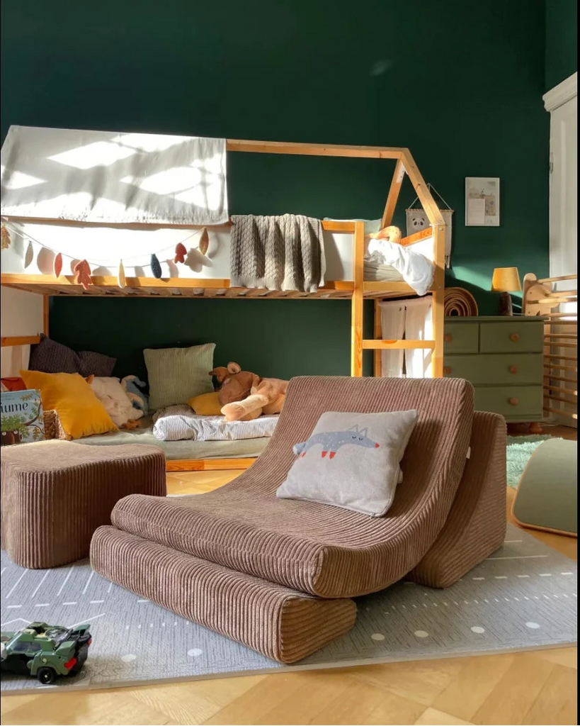 Children's room with a house-shaped bed and brown lounge chair against a green wall.