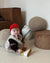 Toddler in a wool vest sitting beside Wigiwama corduroy poufs in a minimal, modern living space
