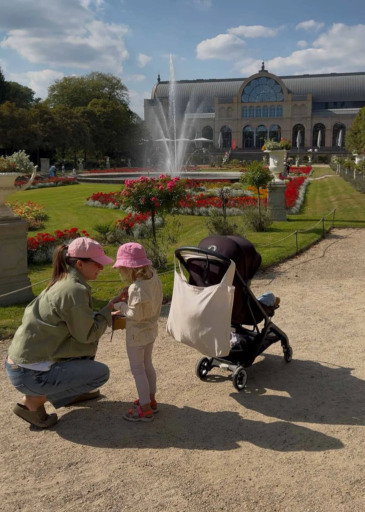 A mother kneels beside her young daughter in front of the fountain and flowerbeds at Flora and Botanical Garden in Cologne.