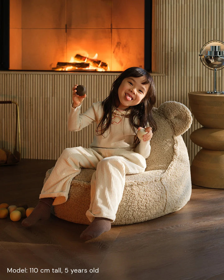 Child relaxing in Wigiwama Biscuit Bear Beanbag in a cosy home interior
