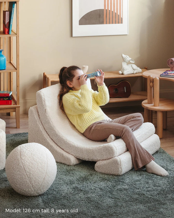 Child relaxing in Wigiwama Cream White Moon Chair in a cosy home interior