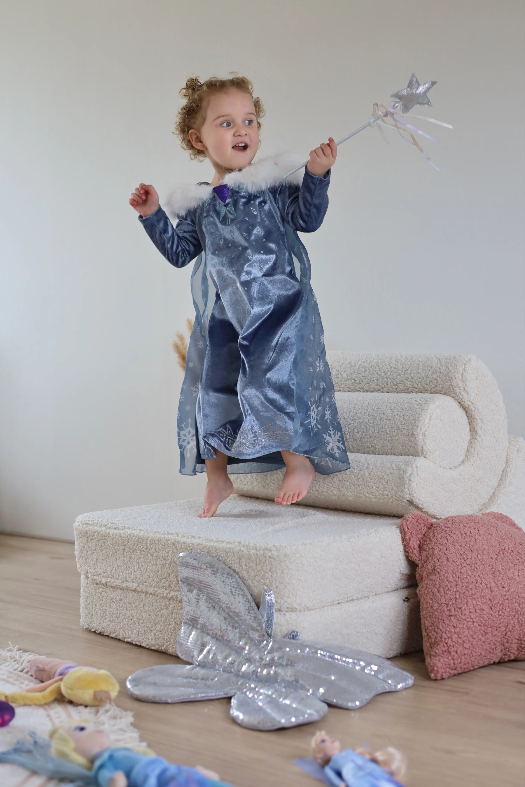 Girl dressed as a fairy queen balancing on a white boucle Wigiwama play set, ready to cast magic in her playroom