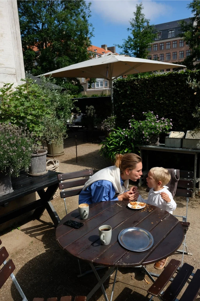 Lea Sørensen sharing a quiet moment with her son over coffee and pastries at Hercules Pavilion in Copenhagen.