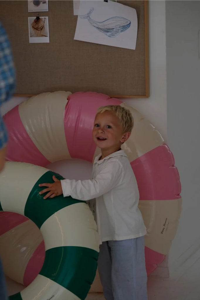 A child smiling and playing with oversized inflatable swim rings at COlabel in Copenhagen.