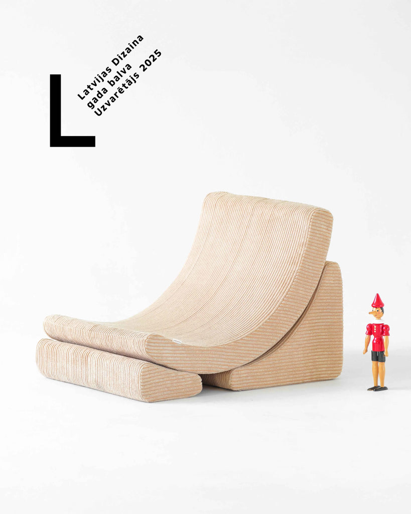The award-winning Wigiwama Moon Chair in beige corduroy, displayed in a clean white setting next to a Pinocchio toy and the National Design Award 2025 badge.