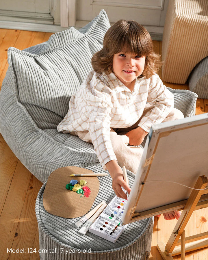 Child relaxing in Wigiwama Peppermint Green Beanbag Chair in a cosy home interior