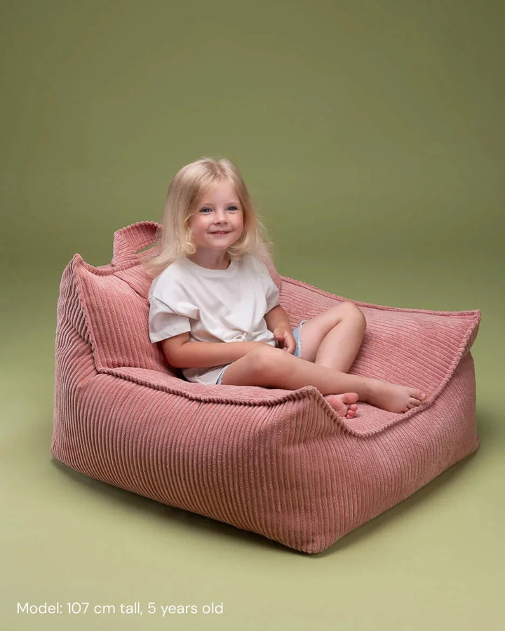 Child relaxing in Wigiwama Pink Mousse Beanbag Chair in a cosy home interior