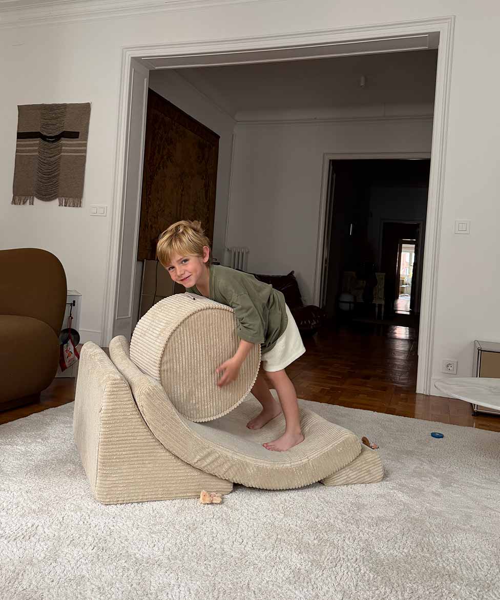 Boy playing in a living room with Wigiwama Brown Sugar Moon Chair and pouffe
