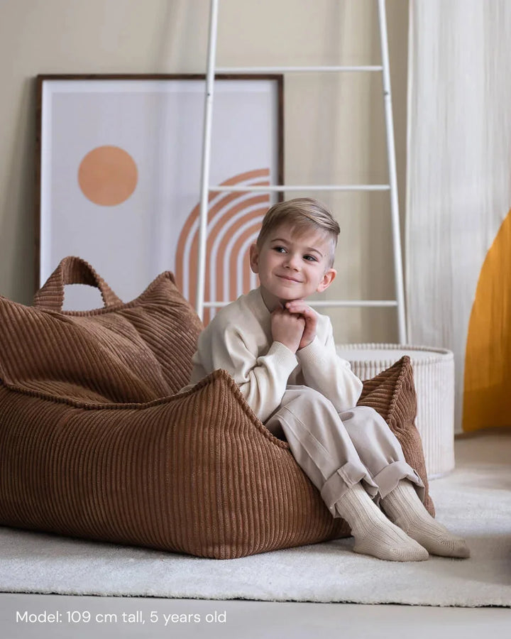 Child relaxing in Wigiwama Toffee Beanbag Chair in a cosy home interior