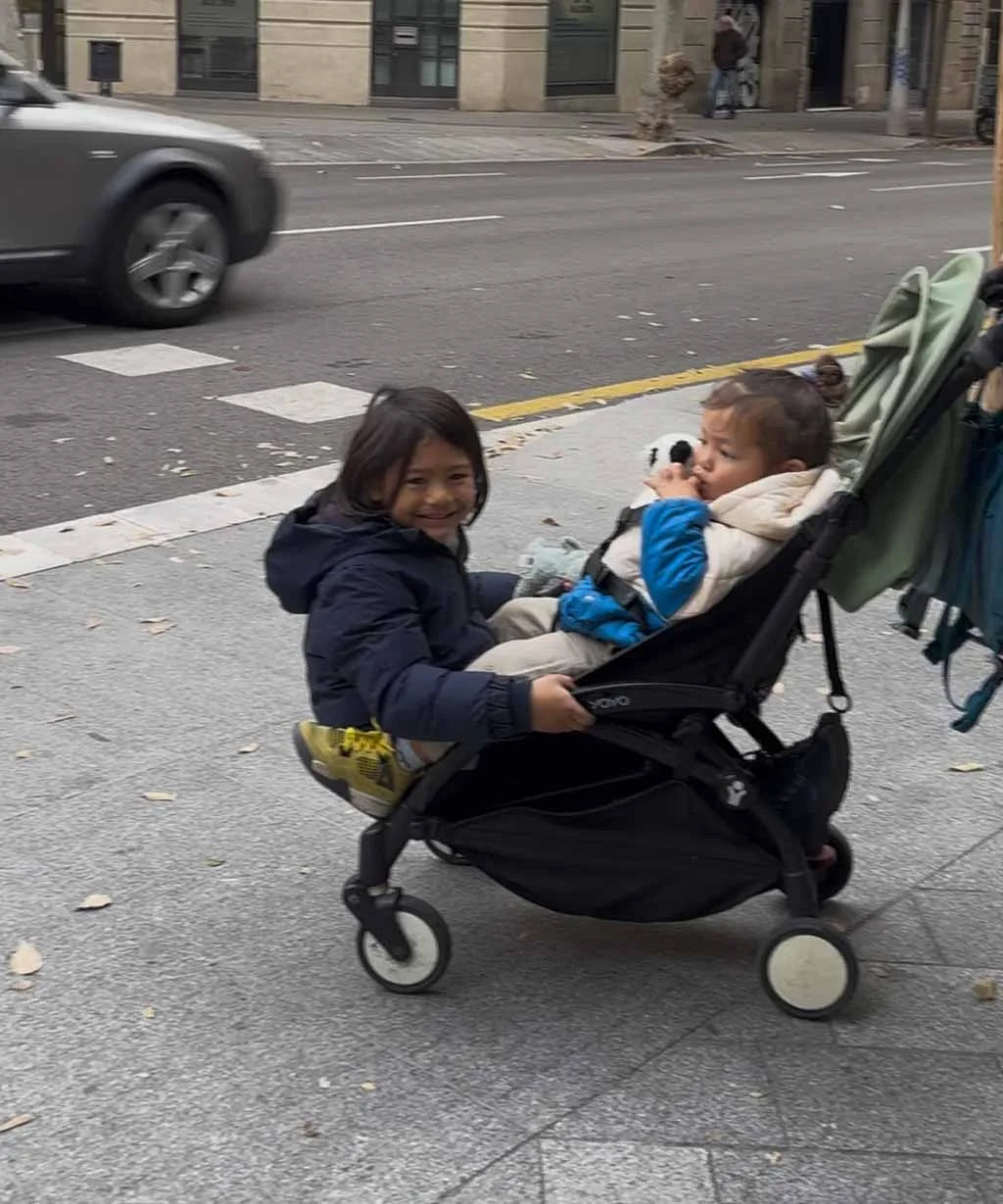 Two children in a stroller on a city street