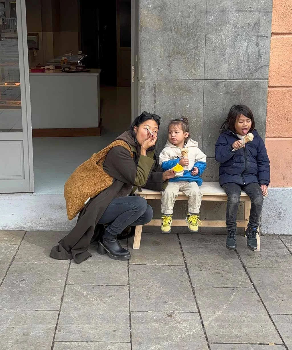 Woman and two children sitting on a bench outside a building