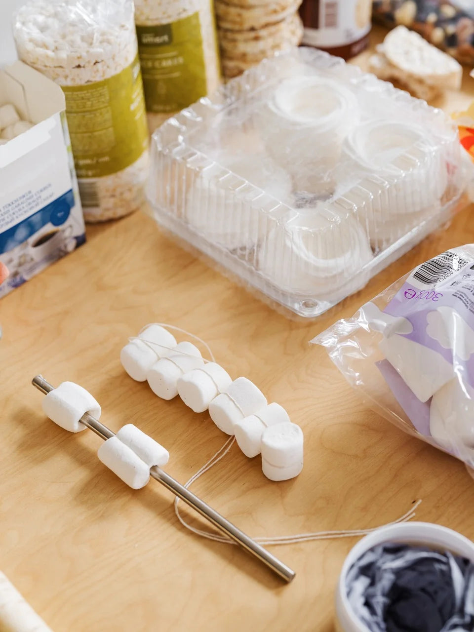 Close-up of marshmallows threaded onto metal and string, surrounded by styling materials used in the Mini Beanbag set.