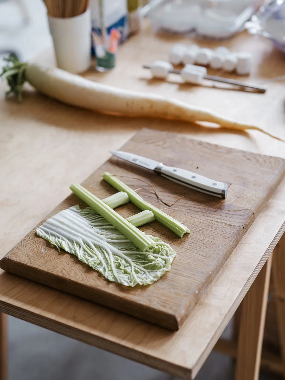 Chopping board with celery and napa cabbage arranged for texture research in Zane Priede’s studio.